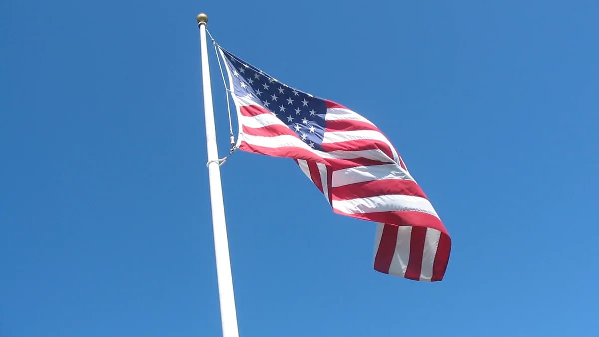 Photo by Kiddo27, licensed under CC BY-SA 4.0 (Wikimedia Commons) The flag of the United States waving in the wind against a clear blue sky